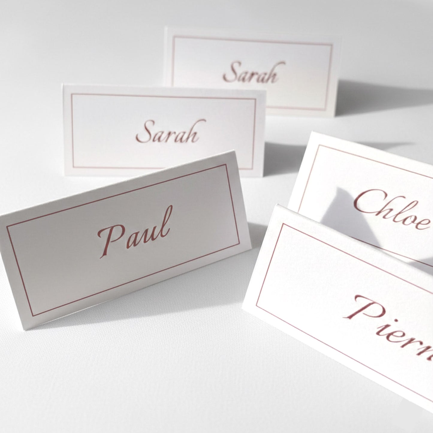 Marque-places personnalisés prénoms invités, cartes de table mariage bordeaux et blanc, décoration de table baptême ou communion, papeterie événementielle élégante, escort cards personnalisées, style classique et épuré, lot de marque-noms pour invités