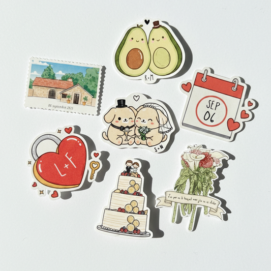 Une collection de sept stickers illustrés sur le thème du mariage, disposés sur un fond blanc épuré avec un éclairage naturel créant des ombres douces. Les autocollants incluent deux avocats amoureux, un couple de chiens en tenue de mariés, un cadenas en forme de cœur rouge marqué 'L+F', un gâteau de mariage à trois étages, un bouquet de fleurs avec un ruban, un calendrier affichant le '06 SEP' et une illustration de maison de campagne de style aquarelle